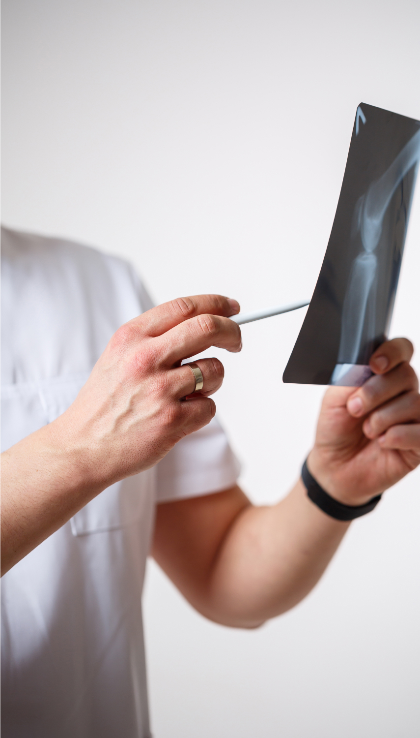 A healthcare professional examining an X-ray of a knee using a pencil.