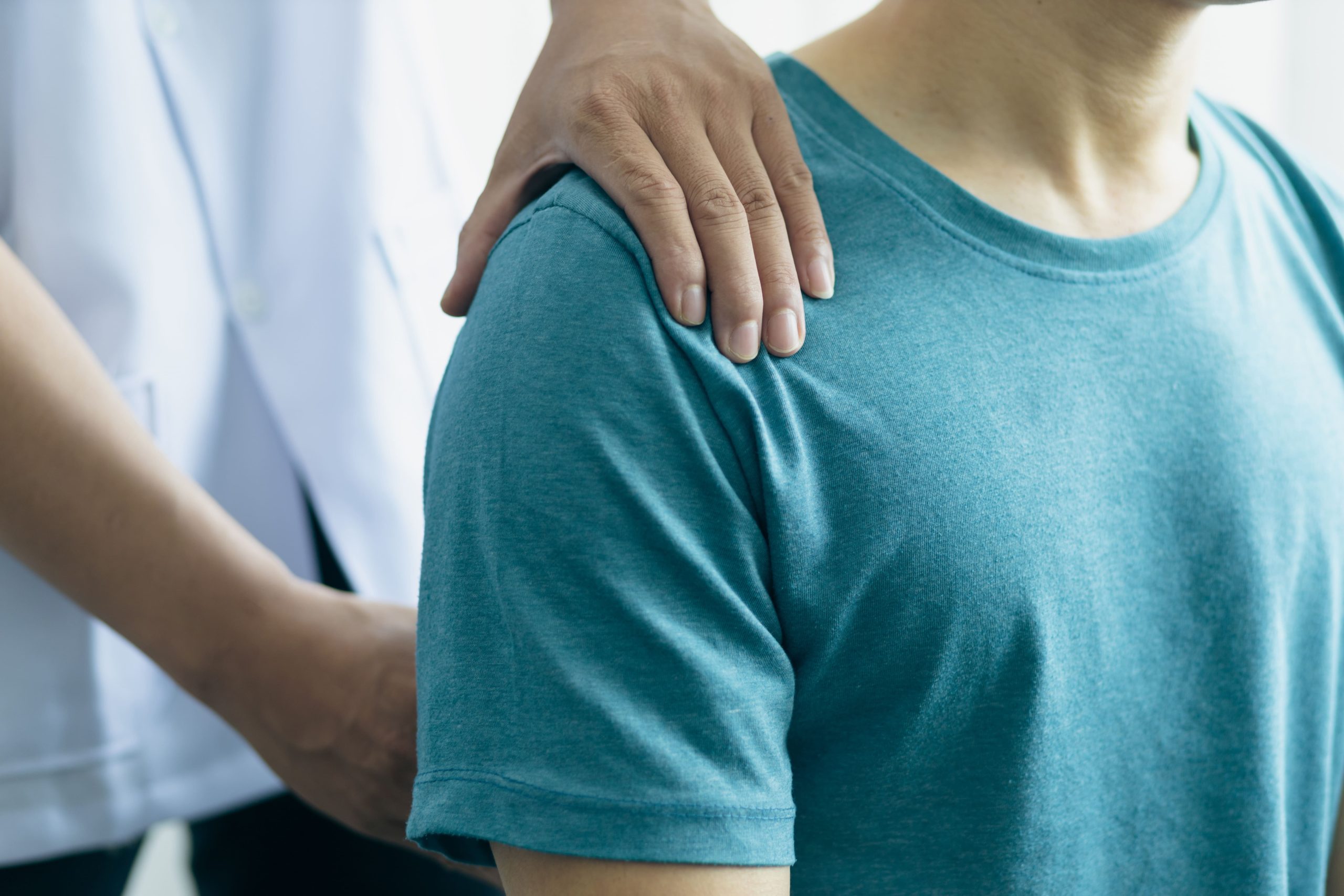 A healthcare professional providing gentle support to a patient during a medical consultation.