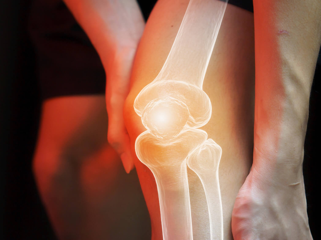 A close-up view of a knee joint with a glowing x-ray effect, highlighting the bones and structure.
