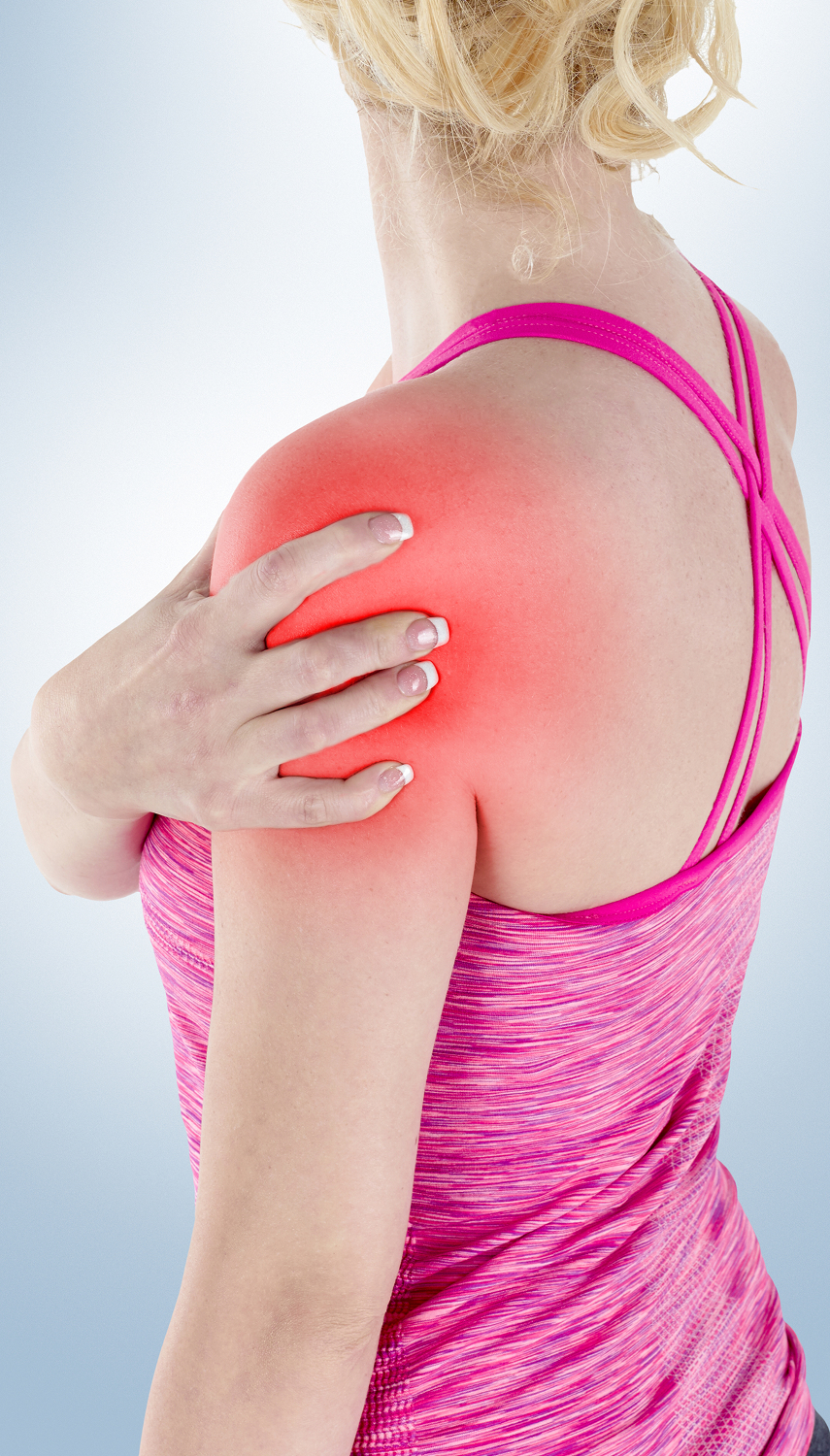 A woman wearing a pink tank top is holding her shoulder, which appears to be in discomfort.