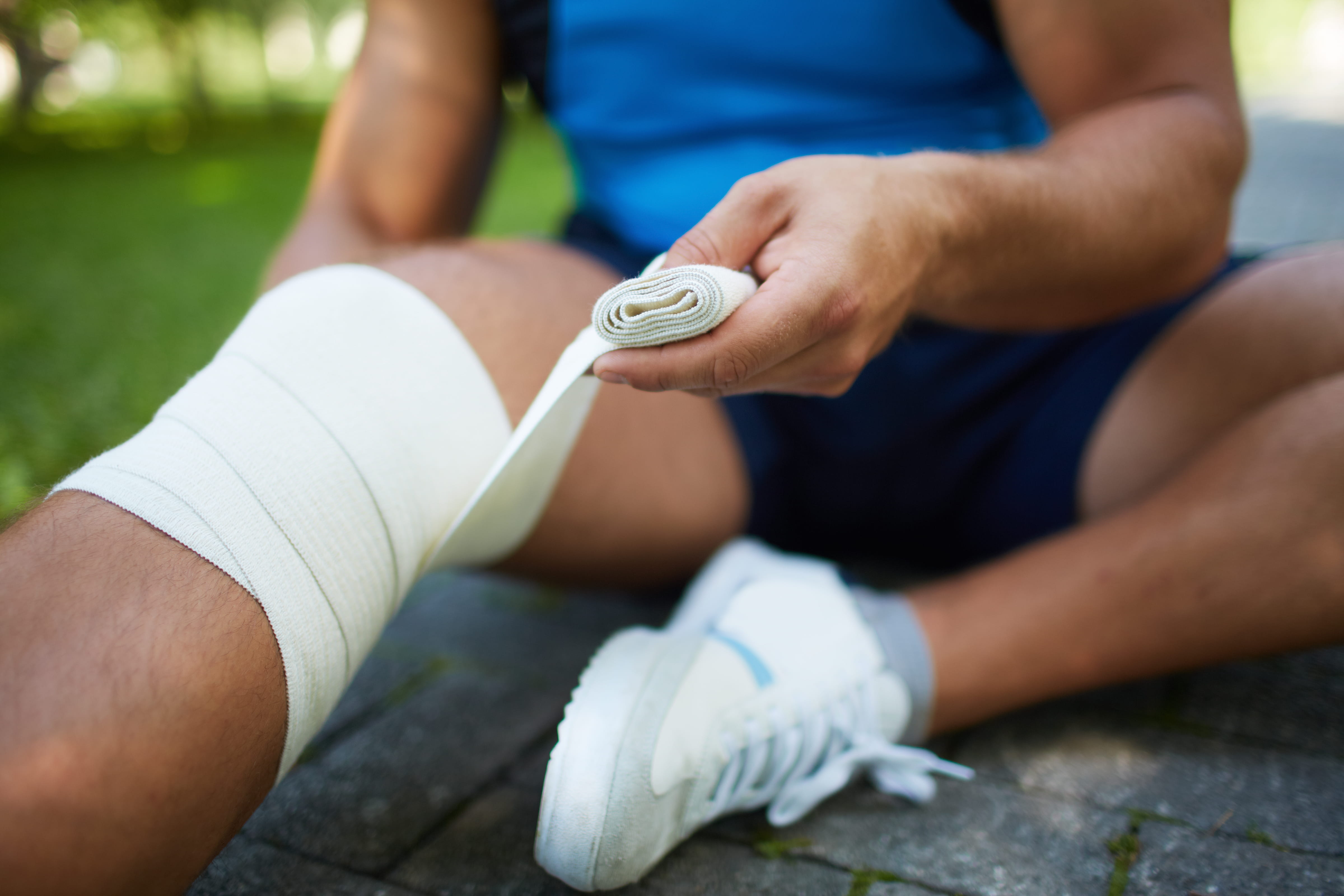 man-taping-his-knee-in-park-2026-09-22-02-58-36-utc (1)