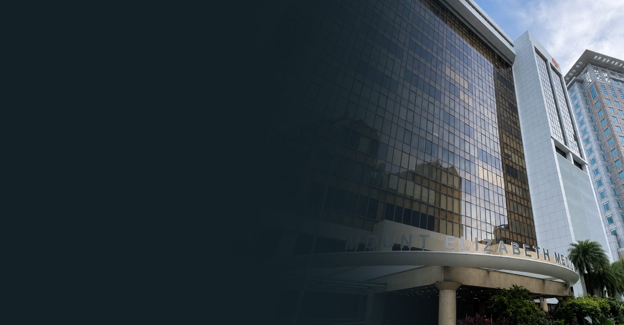 A view of Mount Elizabeth Hospital with large glass windows and modern architecture.